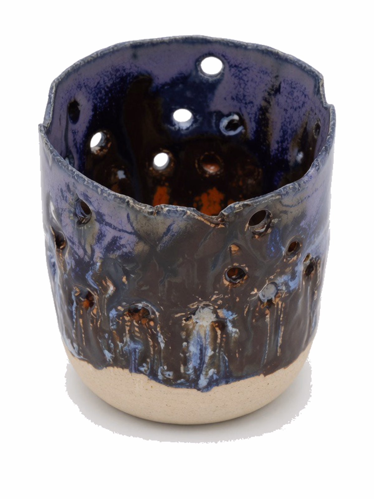 A tall open vessel in deep cobalt glaze, perforated through the wall with circular holes; the glaze breaks darker to iron in places, with the raw stoneware foot showing at the base.