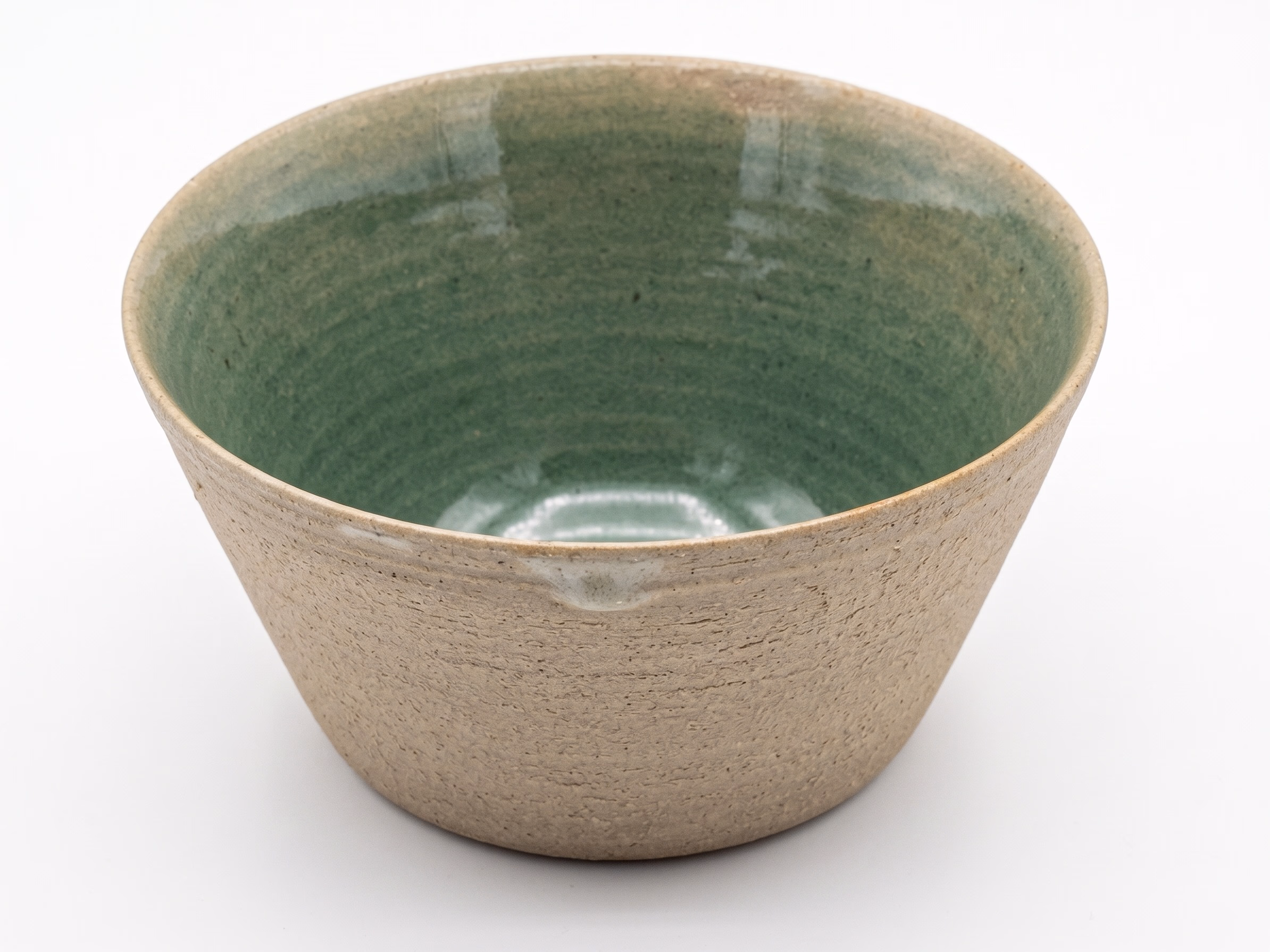 A flared bowl with a raw textured stoneware exterior and a pooling jade-green glazed interior.