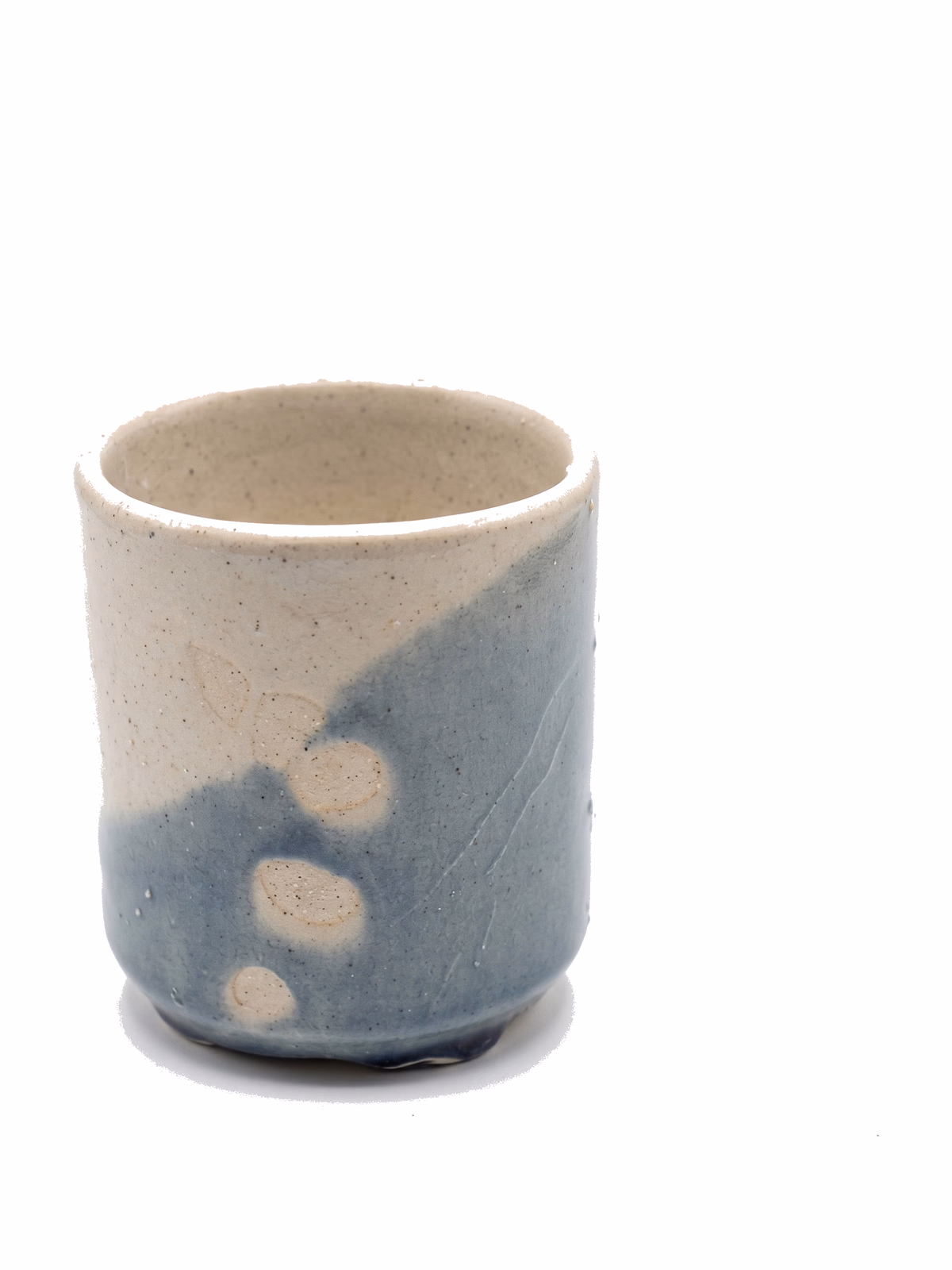 A small straight-sided cup, half cream and half slate-blue, with circular wax-resist marks where the glaze beads away.